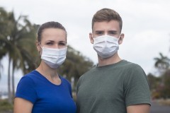 Beautiful serius couple, guy, girl in protective sterile medical mask on face looking at camera outdoors at asian street. Air pollution, virus, new Chinese pandemic coronavirus concept. Man and woman.